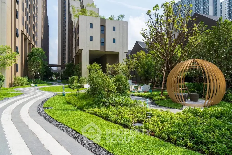 Luxurious modern apartment complex with lush green garden and unique outdoor seating area.