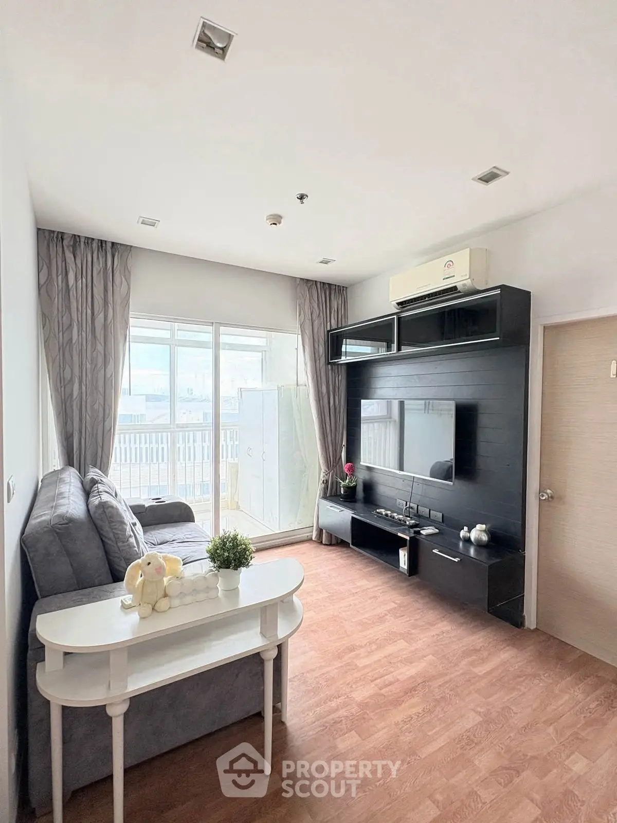 Modern living room with stylish decor and natural light, featuring a cozy sofa and entertainment center.