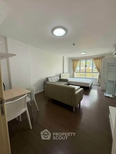 Spacious studio apartment with modern furnishings and large window for natural light.