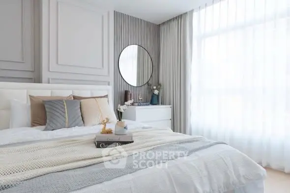 Elegant bedroom with modern decor and large window for natural light.