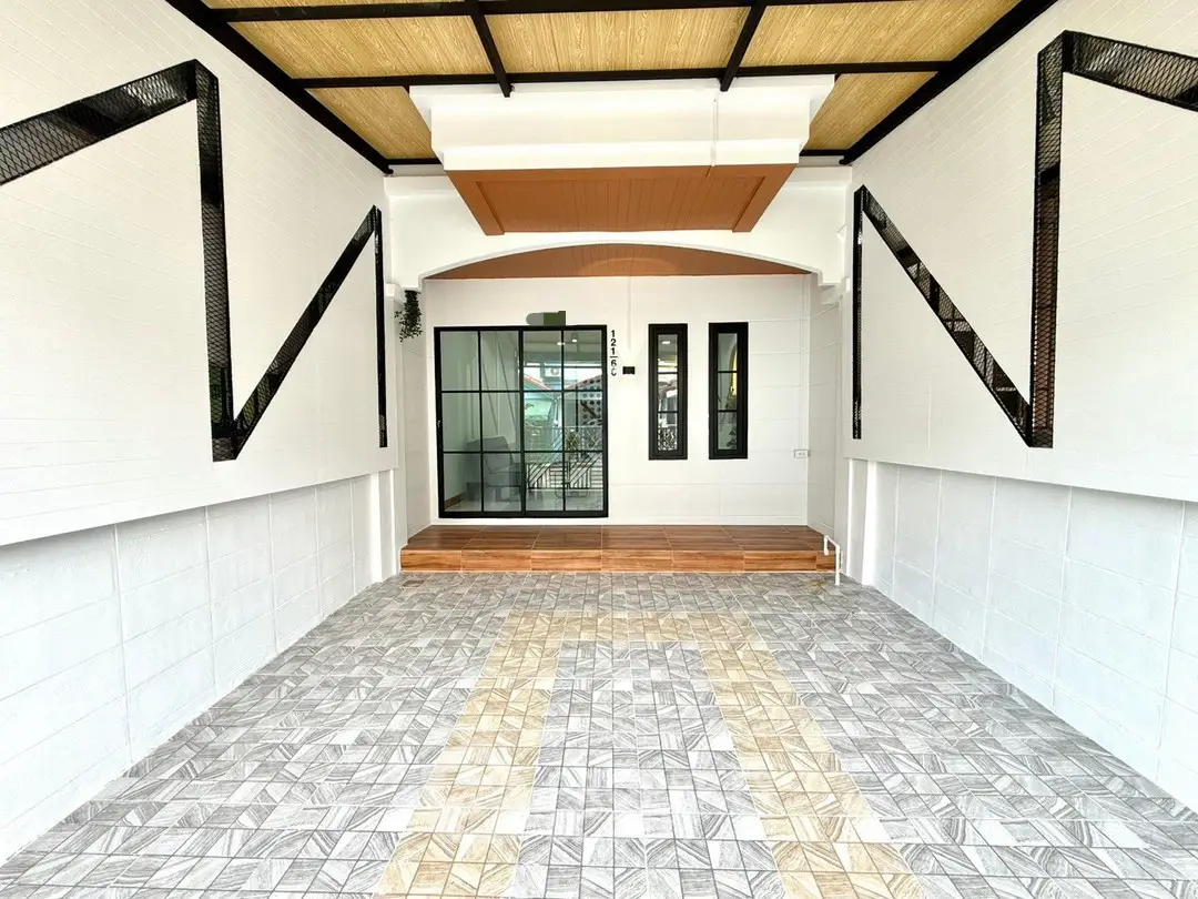 Modern covered parking area with stylish geometric tile design and glass door entrance.