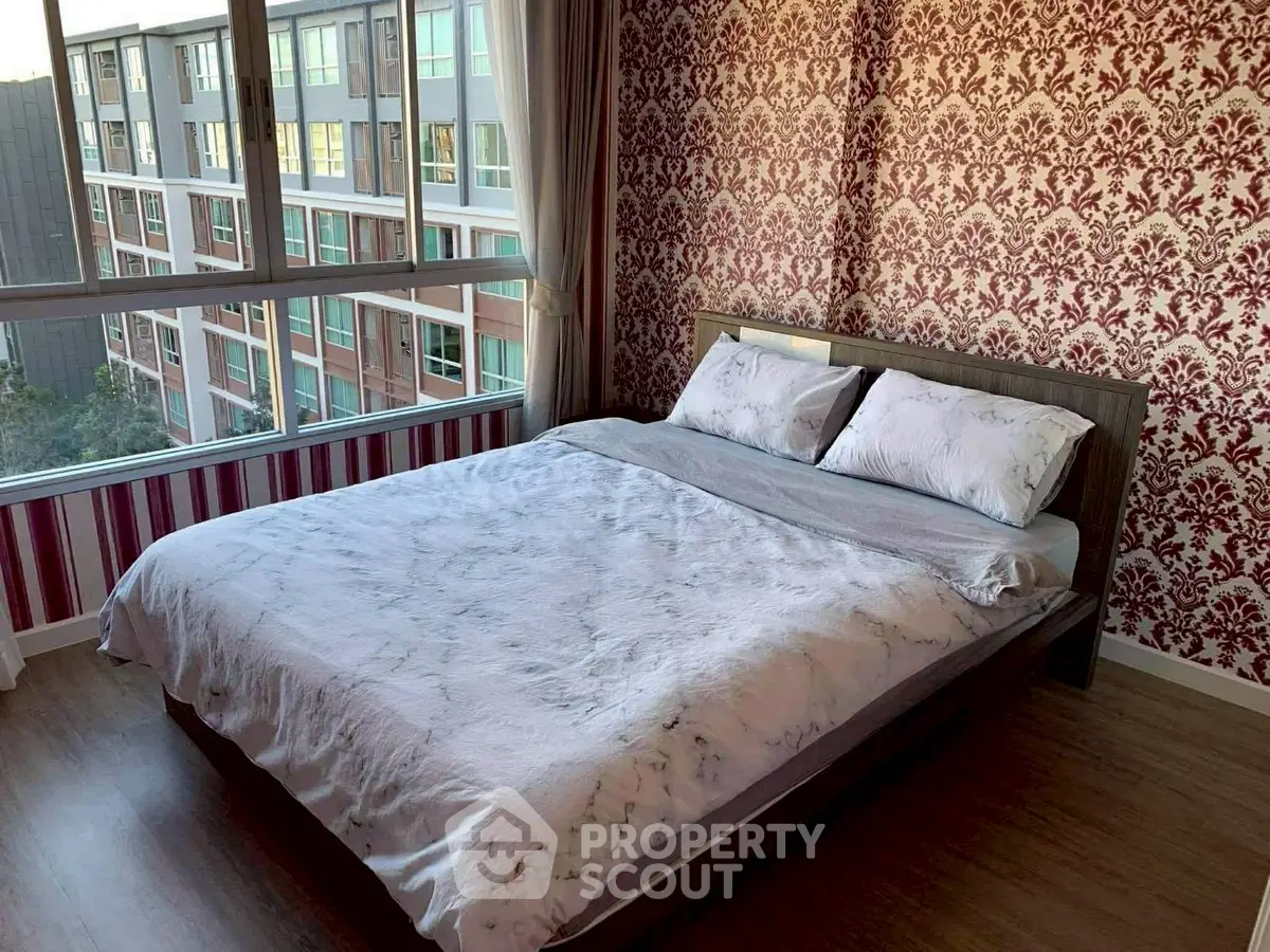 Spacious bedroom with elegant wallpaper and large windows offering natural light.