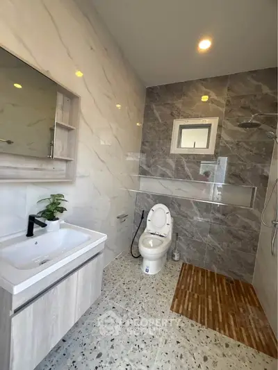 Modern bathroom with sleek design, featuring a stylish sink, toilet, and elegant wall tiles.