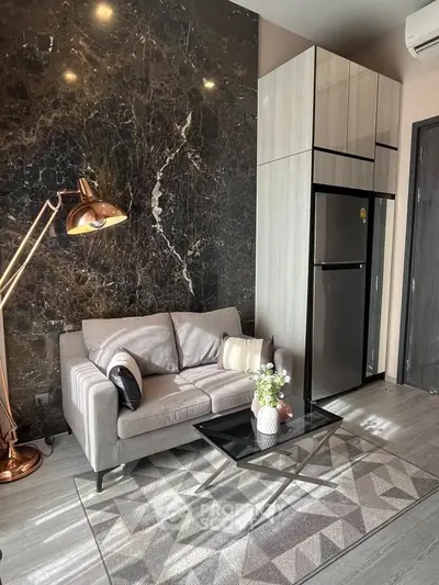 Modern living room with sleek design, featuring a cozy sofa, stylish lamp, and elegant marble wall.