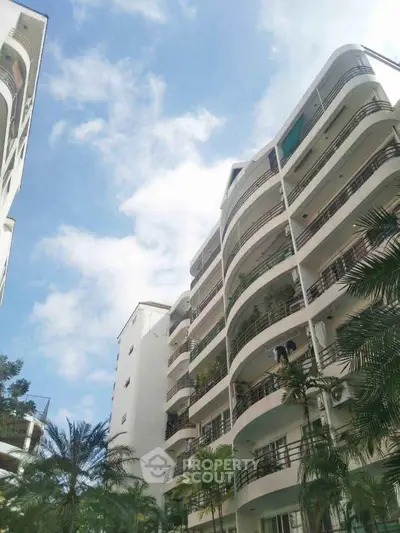 Stunning modern apartment building with lush greenery and spacious balconies.
