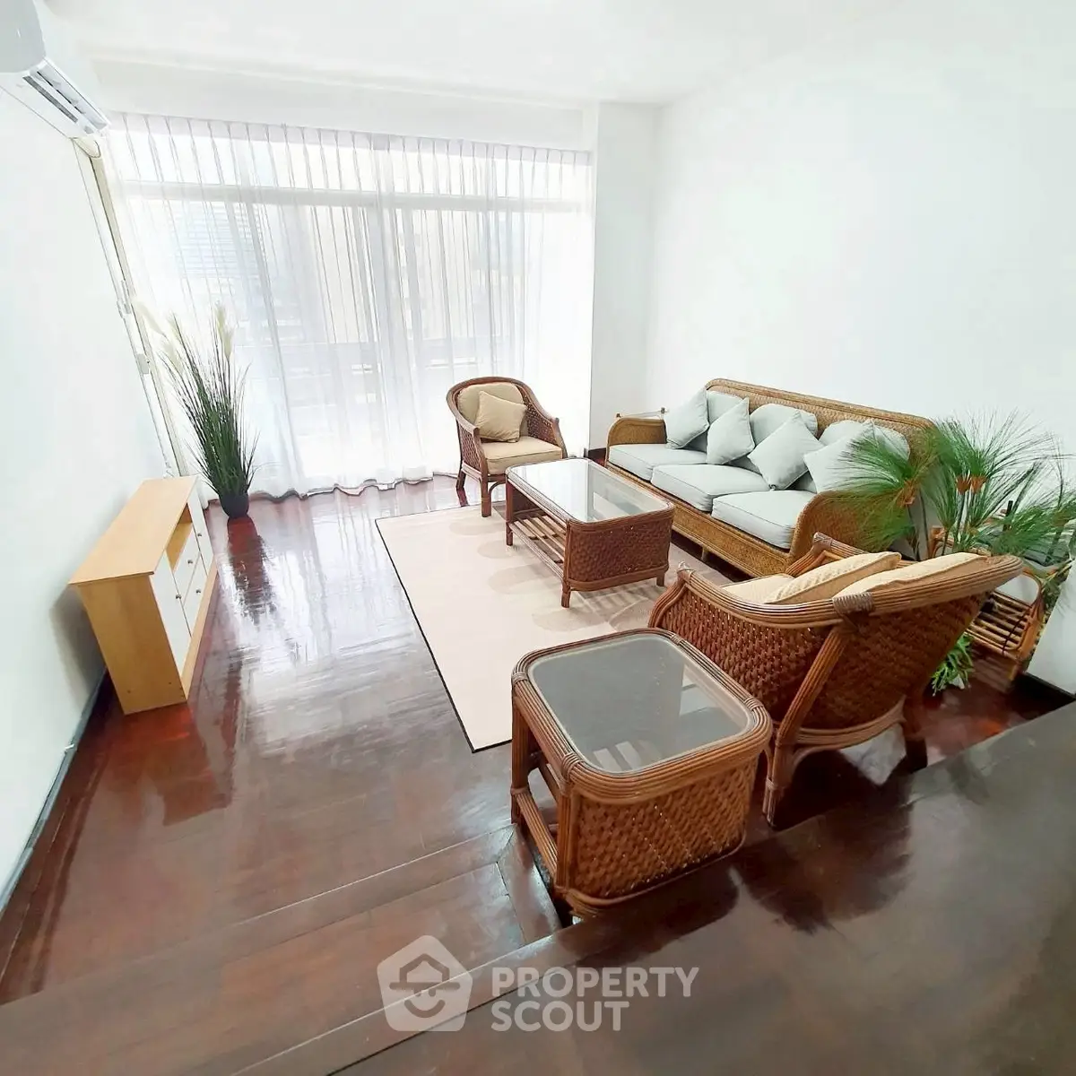 Charming living room with elegant wicker furniture and large windows for natural light.