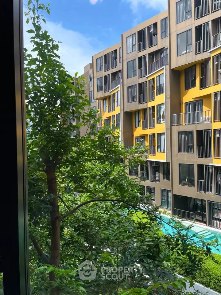 Modern apartment building with vibrant yellow accents and lush greenery view.