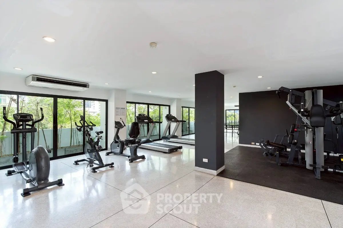 Spacious modern gym with large windows and fitness equipment in a residential building.