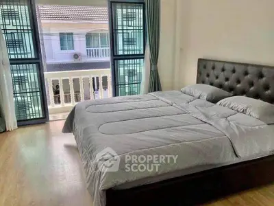 Spacious bedroom with large windows and modern decor in a serene setting.