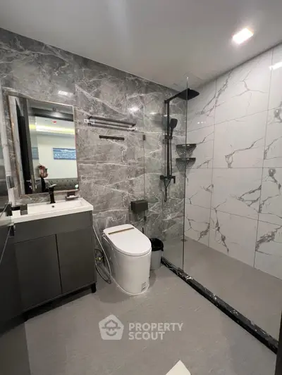 Modern bathroom with sleek design, glass shower, and marble tiles.