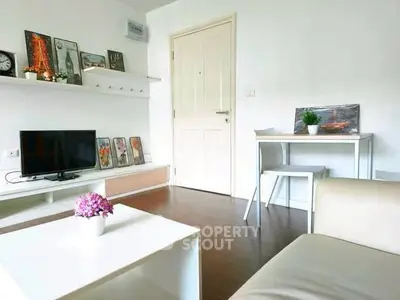 Modern living room with stylish decor and natural light, featuring a cozy seating area and a sleek TV setup.