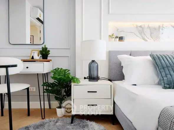Modern bedroom with stylish decor, featuring a cozy bed, elegant nightstand, and chic mirror.