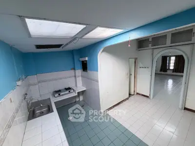 Spacious kitchen with open layout and gas stove, connected to a bright living area.