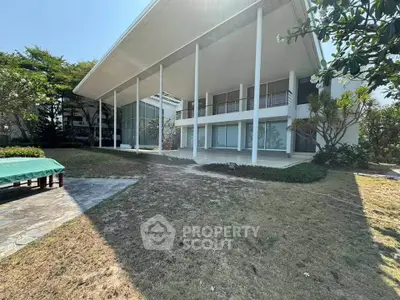 Stunning modern home with expansive glass facade and lush garden, perfect for luxury living.