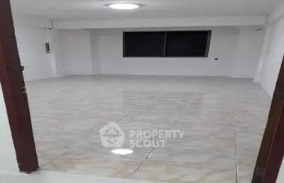 Spacious empty room with tiled flooring and large window, ideal for customization.