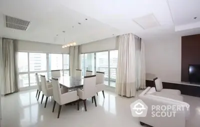 Spacious and elegantly furnished living room with large dining area, modern lighting, and floor-to-ceiling windows allowing abundant natural light.