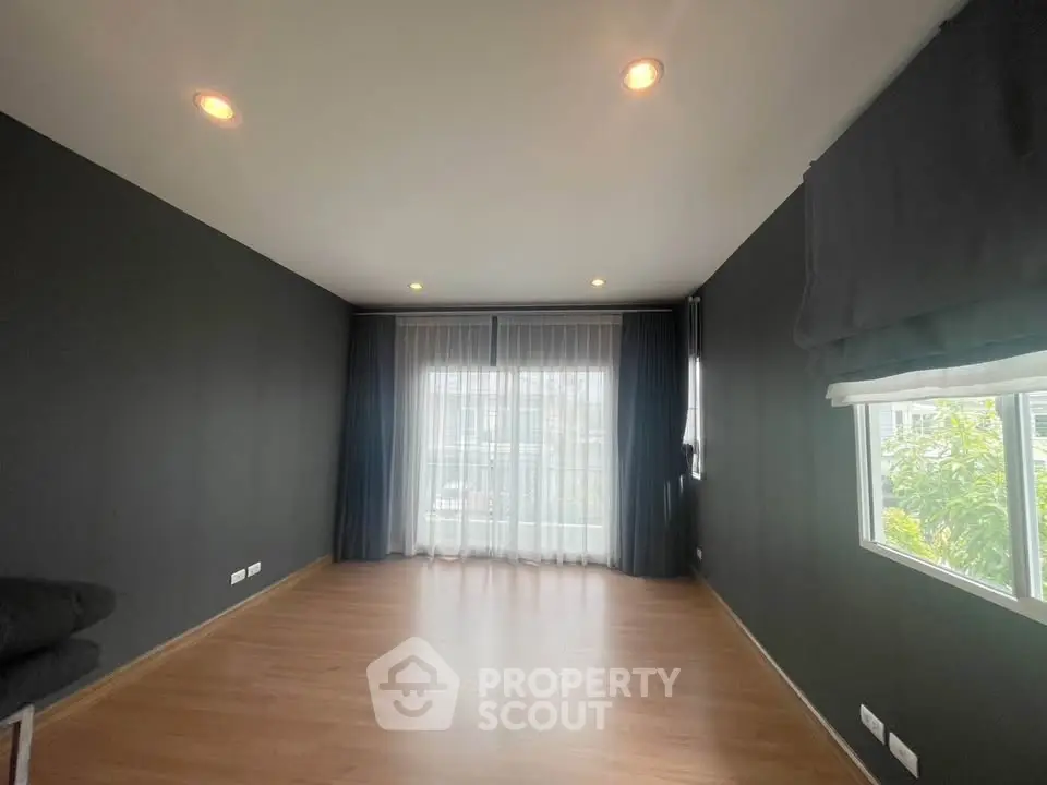 Spacious empty room with large windows and wooden flooring, ideal for customization.