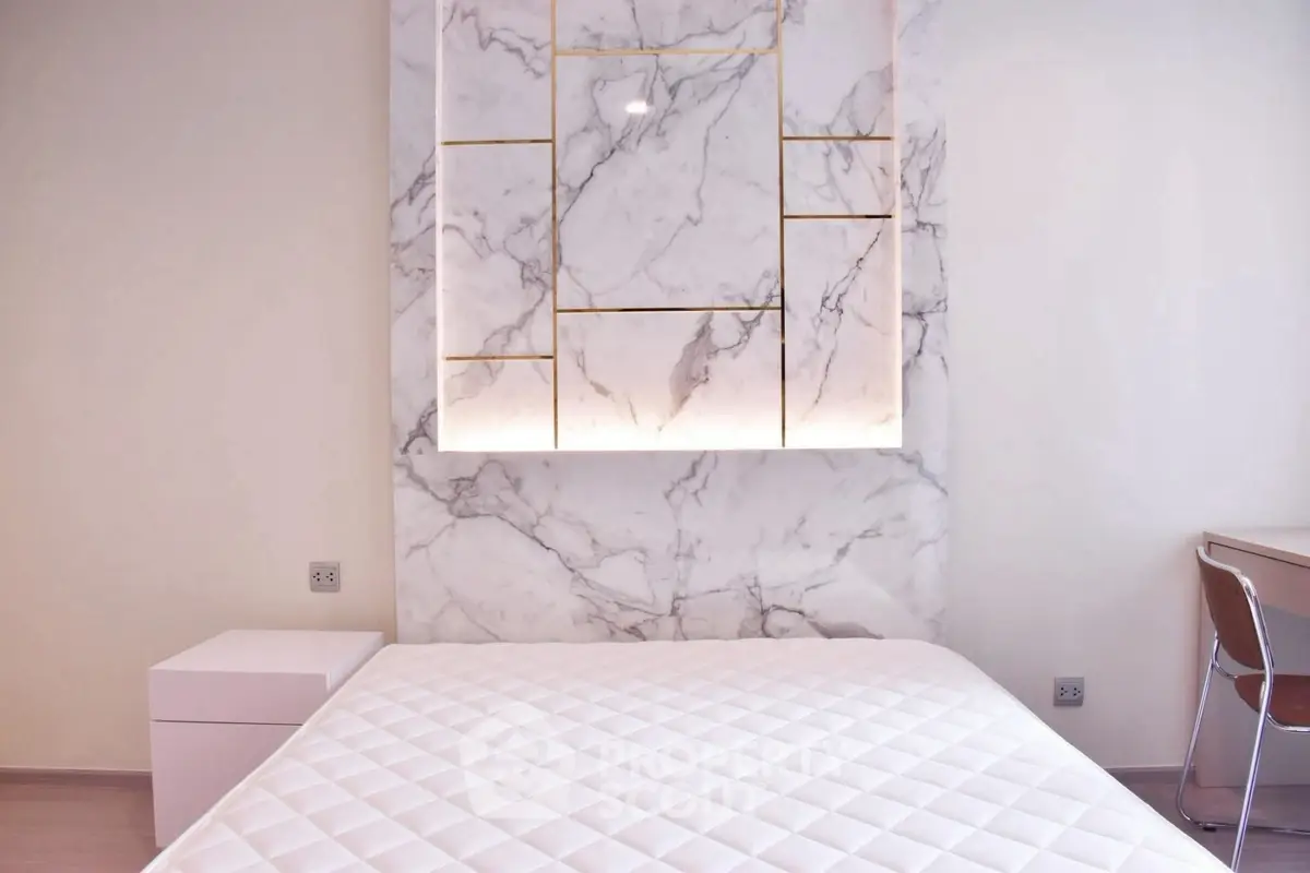 Luxurious bedroom with elegant marble accent wall and modern furnishings.
