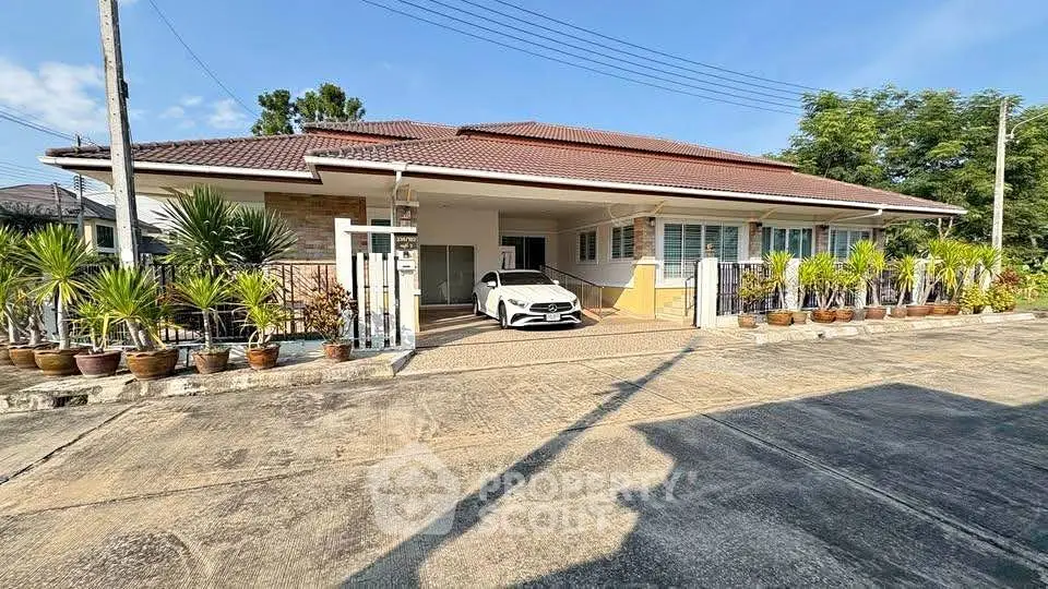 Charming single-story home with spacious driveway and lush potted plants in a serene neighborhood.