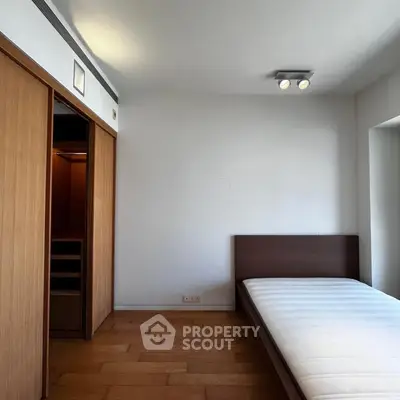 Minimalist bedroom with wooden flooring and built-in closet