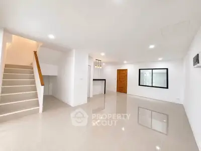 Spacious modern living room with sleek tile flooring and staircase, ideal for contemporary living.