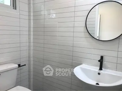 Modern bathroom with sleek white tiles and round mirror
