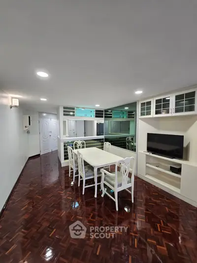 Spacious dining area with elegant furniture and built-in TV unit in modern apartment.