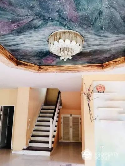 Spacious two-story home interior with grand staircase and unique cosmic ceiling art, featuring elegant chandelier and modern design elements.