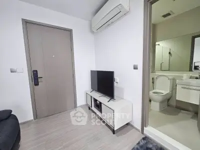 Modern living room with sleek TV setup and adjacent bathroom in contemporary apartment.
