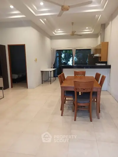 Spacious open-plan dining area with modern kitchen and elegant wooden furniture.