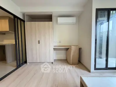 Modern apartment interior with sliding doors and air conditioning, featuring a compact workspace and wooden flooring.