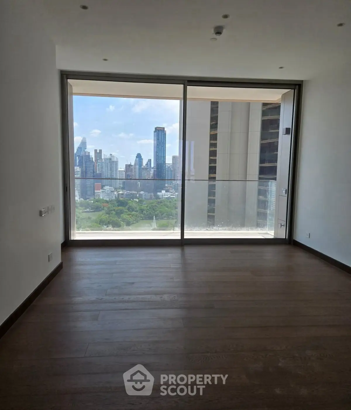 Spacious room with floor-to-ceiling windows offering stunning city skyline views.