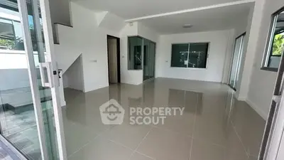 Spacious modern living room with large windows and glossy tiled floors in a contemporary home.