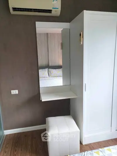 Modern bedroom with sleek white wardrobe and air conditioning unit.