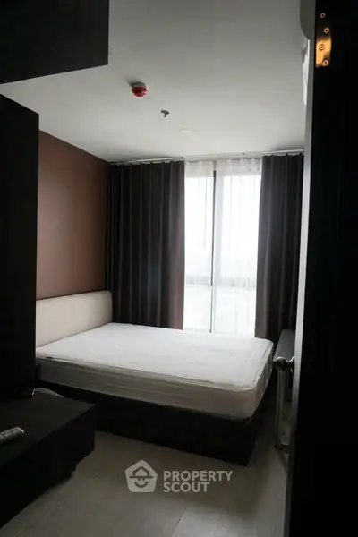 Modern bedroom with large window and minimalist design in urban apartment.