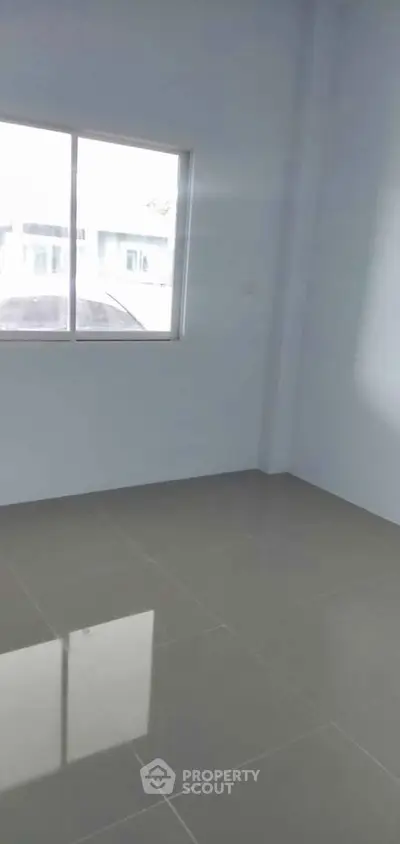 Spacious empty room with large window and glossy tiled floor, perfect for customization.