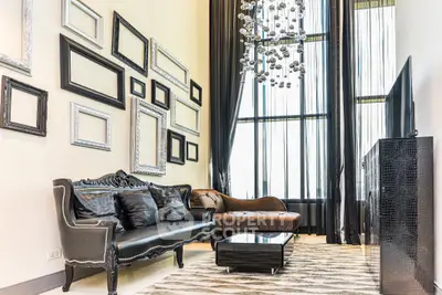 Luxurious living room with high ceilings, elegant chandelier, and stylish decor.