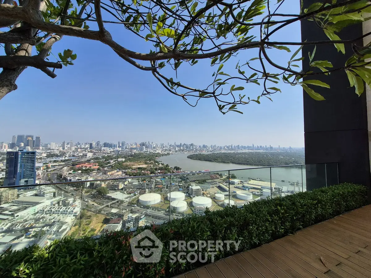 Stunning cityscape view from a high-rise balcony with lush greenery and river backdrop.