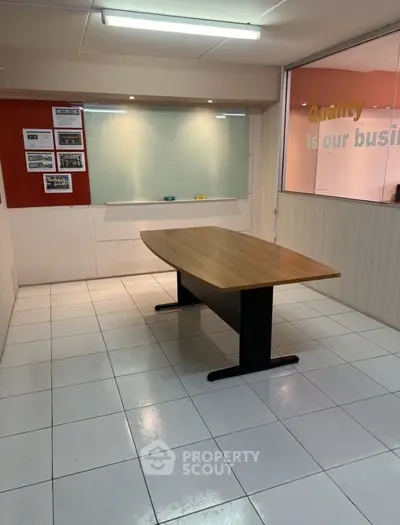 Spacious office room with modern table and whiteboard, ideal for meetings and collaborative work.