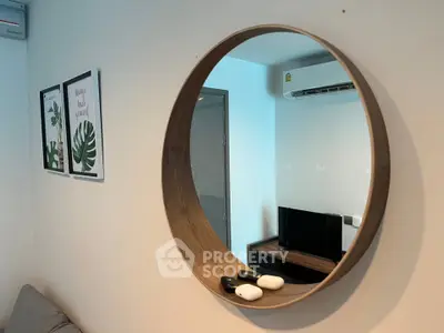 Modern living room with stylish round mirror and wall art, featuring a sleek air conditioning unit.