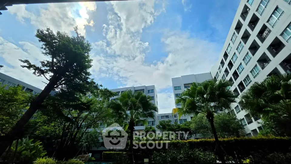 Stunning view of modern apartment complex with lush greenery and blue sky.