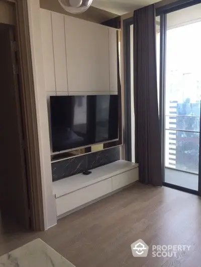 Modern living room with sleek built-in TV cabinet and large window allowing ample natural light, perfect for cozy urban living.