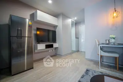 Modern living room with sleek design, featuring a stainless steel fridge and cozy dining area.