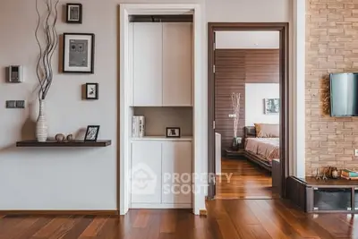 Modern interior with wooden flooring, stylish decor, and a glimpse into a cozy bedroom.