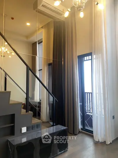 Elegant two-story living space with modern staircase, high ceilings, and chic chandelier, leading to a sunlit balcony with sheer curtains.