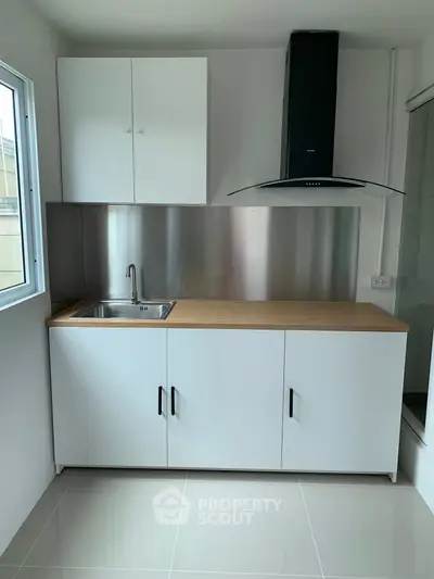 Modern minimalist kitchen with sleek cabinetry and stainless steel backsplash