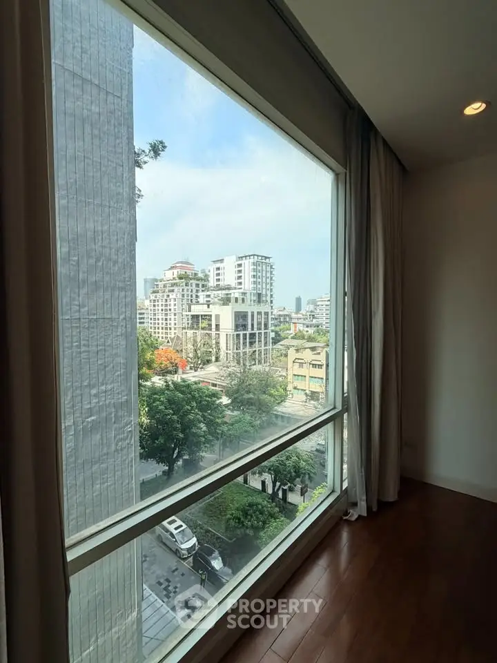 Spacious apartment with large window offering stunning city view, perfect for urban living.
