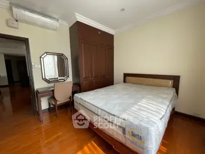 Spacious bedroom with wooden flooring and elegant furniture in a modern apartment.