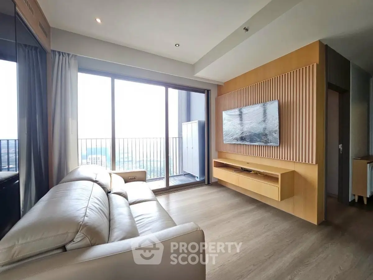 Modern living room with large balcony and sleek design in high-rise apartment.