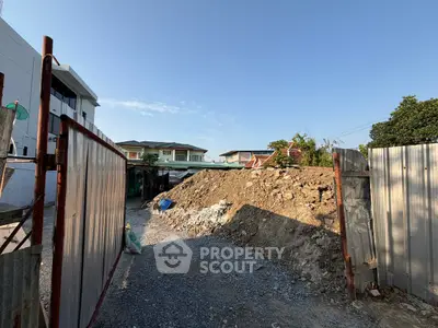 Vacant land plot ready for development in a residential neighborhood with clear blue skies.